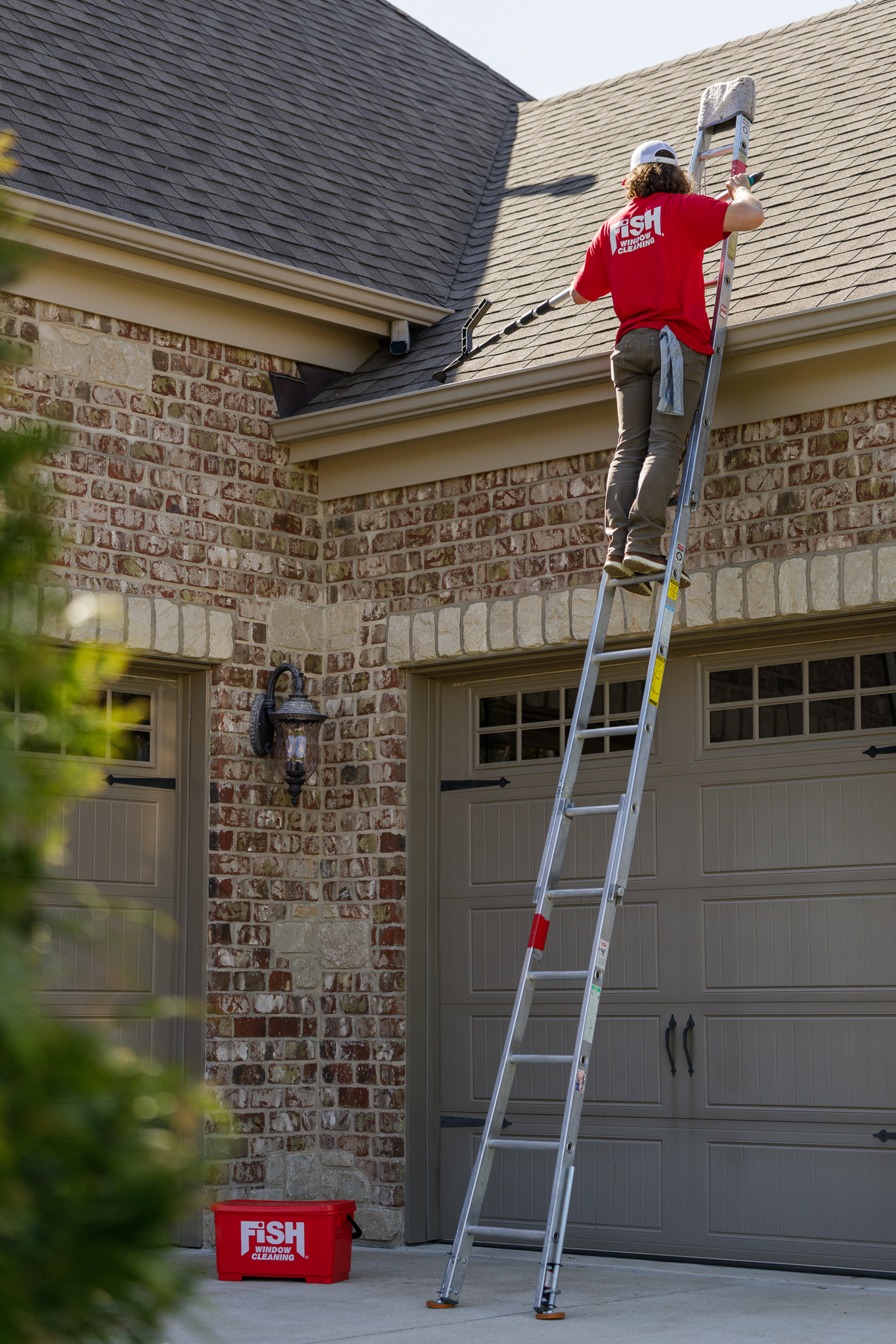Fish Window Cleaner on Ladder Using Tool to Clean Gutters